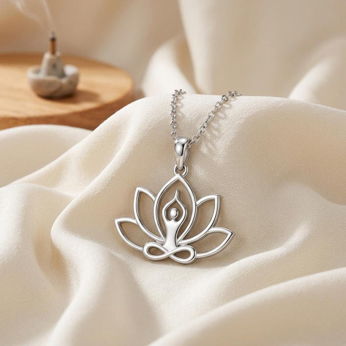 Silver Meditation Lotus Necklace with openwork lotus pendant displayed on ivory satin beside a tabletop scene