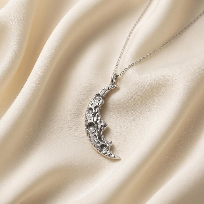 Silver Moon Fragment Pendant Necklace with raised circular crater details on ivory satin