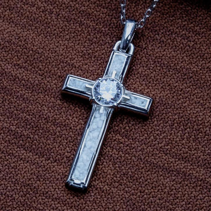 Close-up of the Moonstone Cross Necklace with framed pale cross-arm panels and a round center stone on brown textured fabric