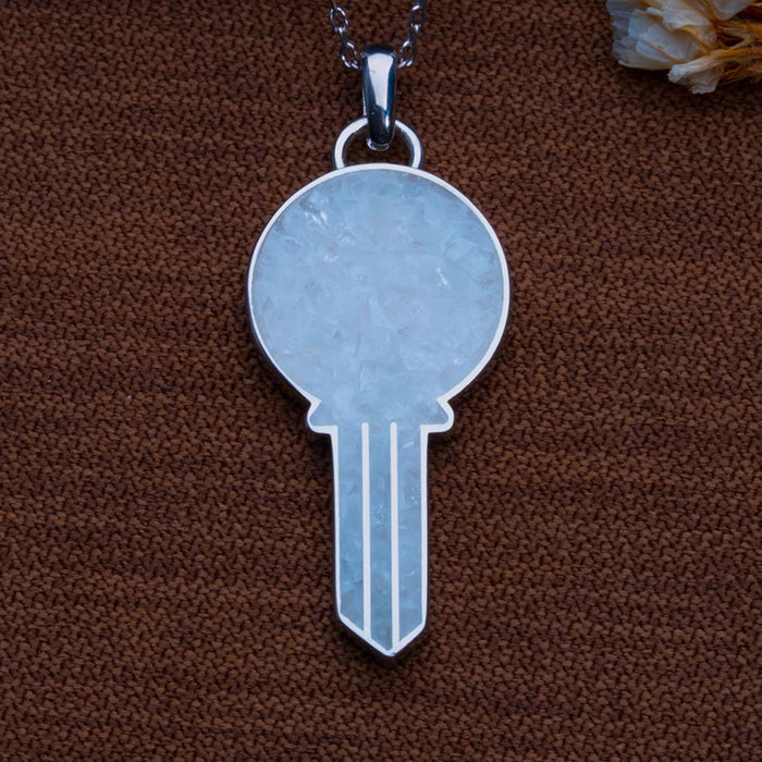 Close view of the round moonstone key pendant on textured brown fabric