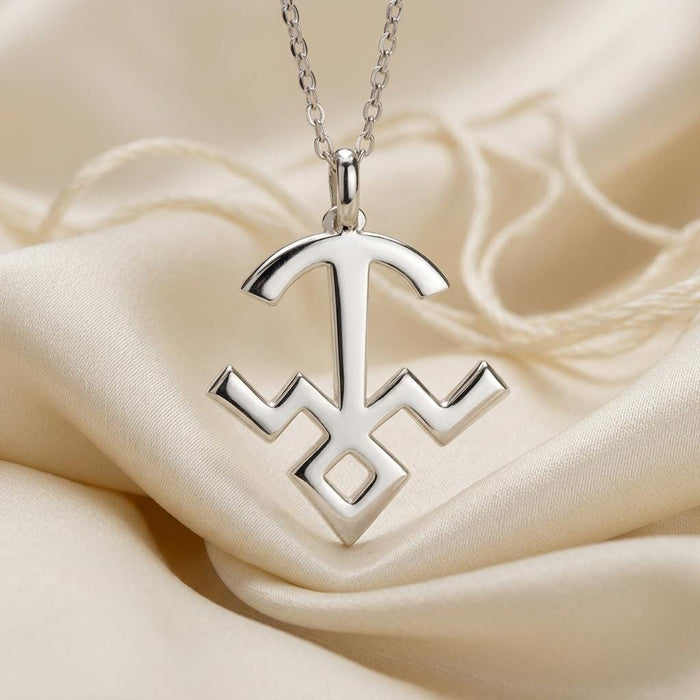Close-up of the polished Mula symbol pendant on ivory satin fabric