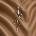 Silver Mystic Forest Branch Pendant Necklace with asymmetric twig-like offshoots on brown fabric