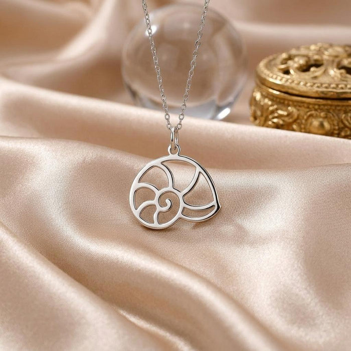 Close-up of the openwork nautilus shell pendant on champagne satin beside a decorative box