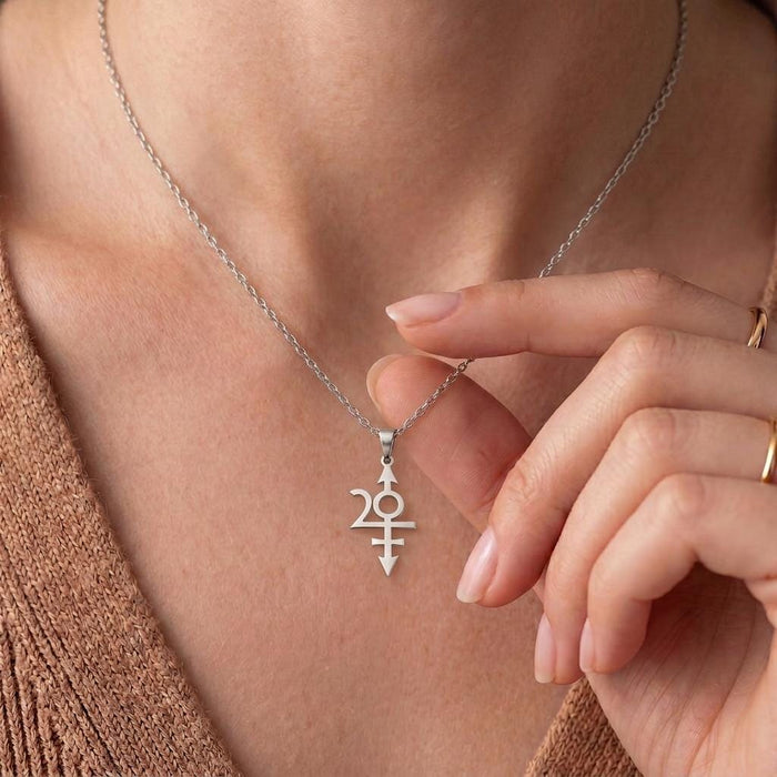 Nibiru Symbol Necklace at the neckline with a hand beside the pendant