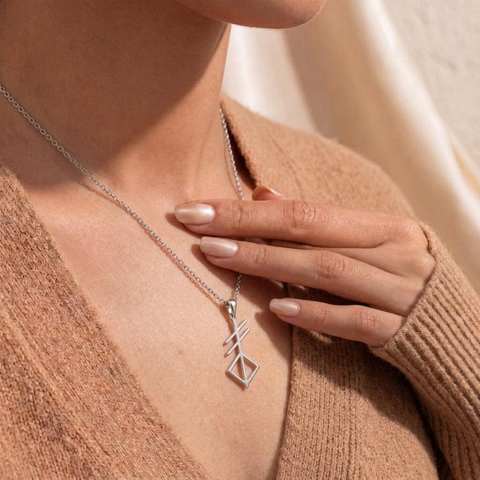 Silver Norse Creation Symbol Necklace worn with a tan knit cardigan