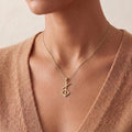 Gold Plated Silver Norse Renewal Symbol Necklace worn with a peach knit V-neck top