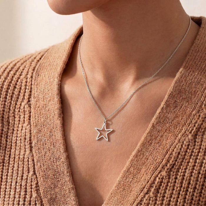 Close neckline view of a five-point outlined pendant necklace worn with a textured tan knit