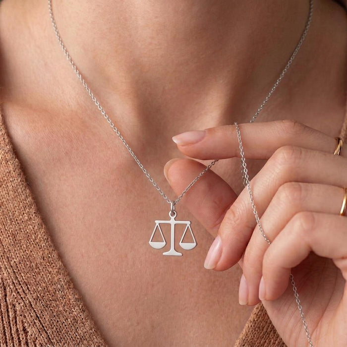 Close-up of the Scales of Justice pendant held near the neckline