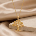 Gold Plated Silver Orchid Tree Pendant Necklace with petal-shaped blossoms displayed on beige satin beside a light stone block