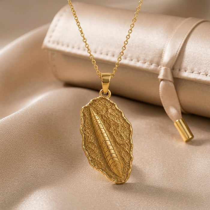 Gold Plated Silver Orthoceras Fossil Pendant Necklace on champagne satin beside a closed jewelry case