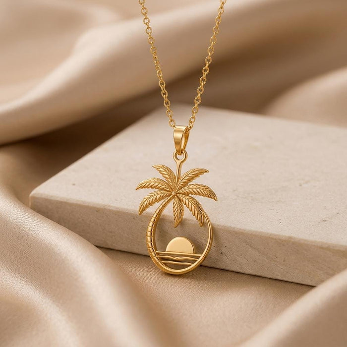 Gold Plated Silver Palm Sunset Pendant Necklace displayed on a light stone block with champagne satin
