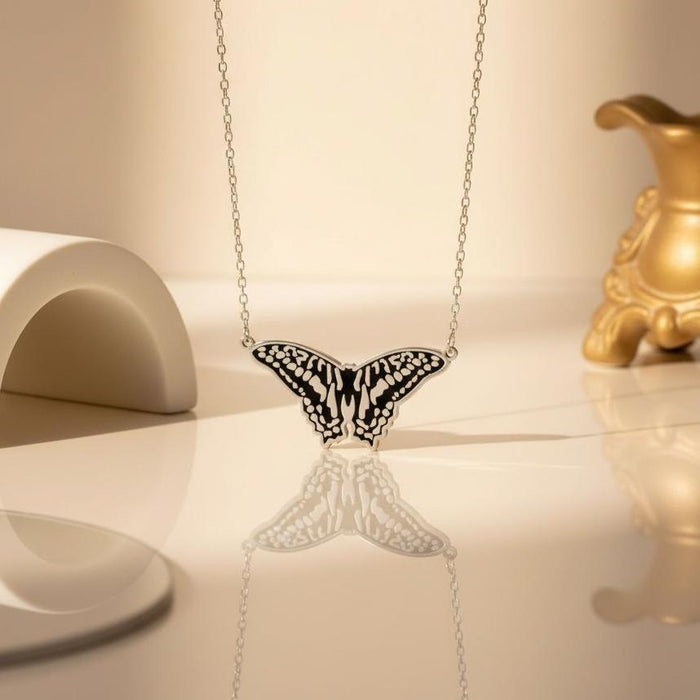 Close view of the patterned butterfly pendant above a reflective cream surface