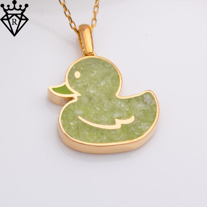 Front close-up of a gold-tone duck pendant with pale green textured detail on a white background