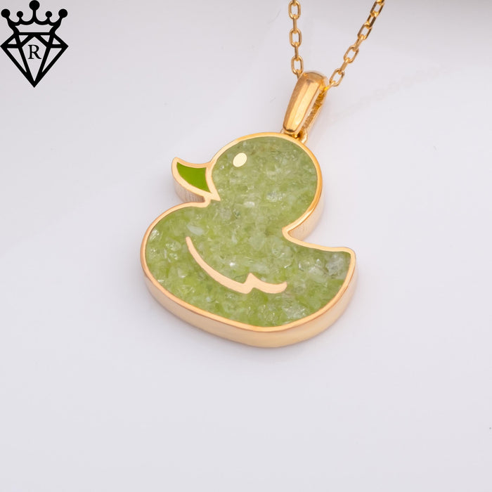 Angled close-up of a gold-tone duck pendant with pale green textured detail on a white background, catalog view 3