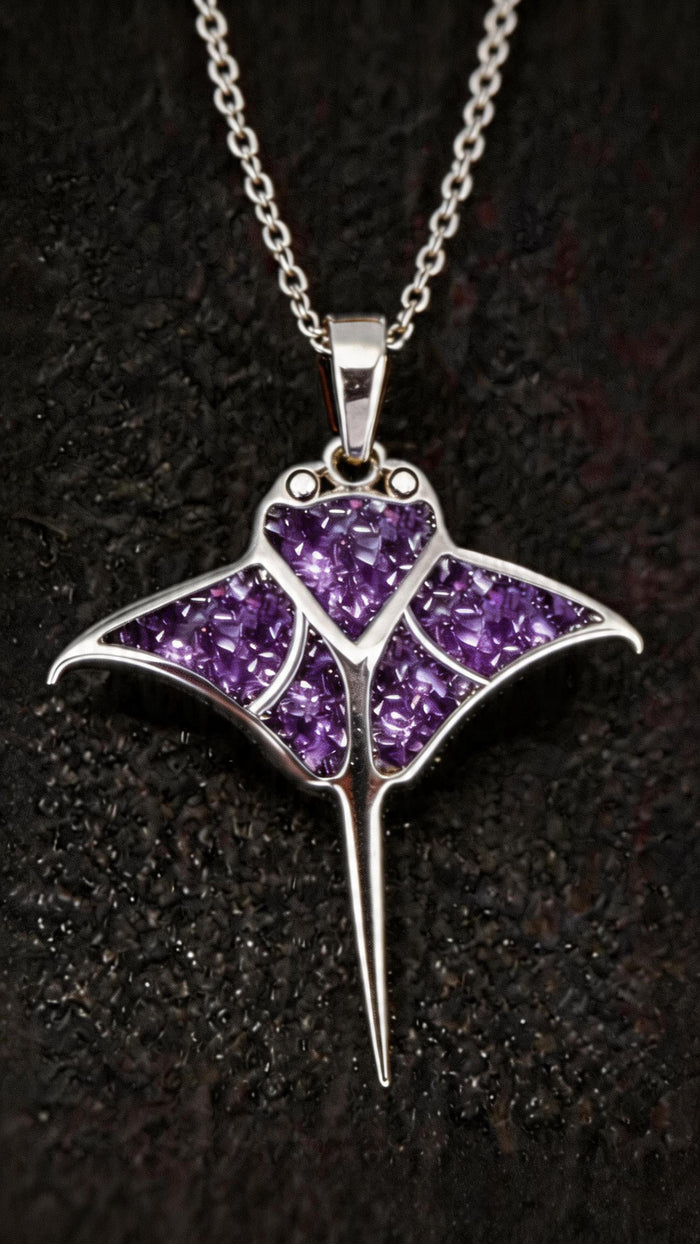 Close-up of the manta ray pendant with purple stone-detail sections on dark fabric