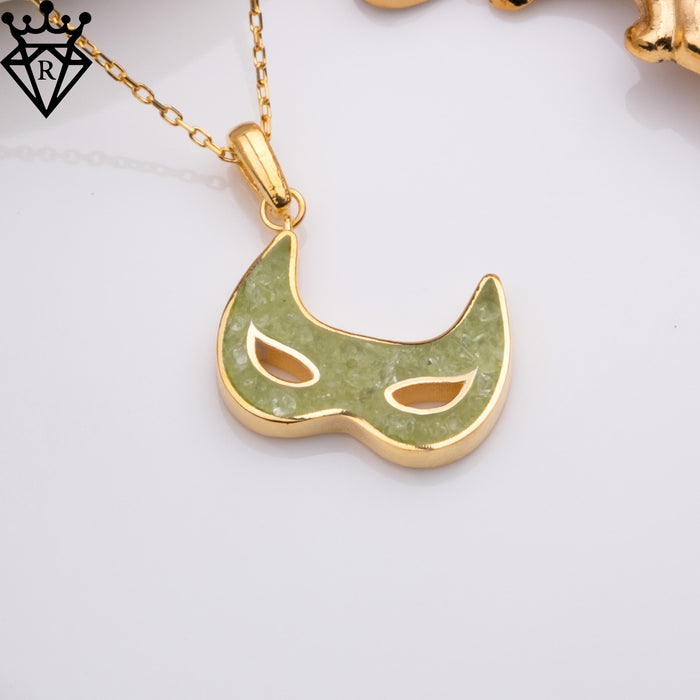 Angled close-up of the Gold Plated Silver peridot mask pendant showing the textured green face and eye cutouts