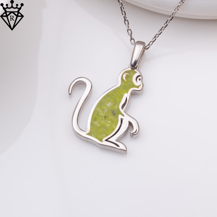 Detail image emphasizing the monkey pendant's curled tail and green central accent