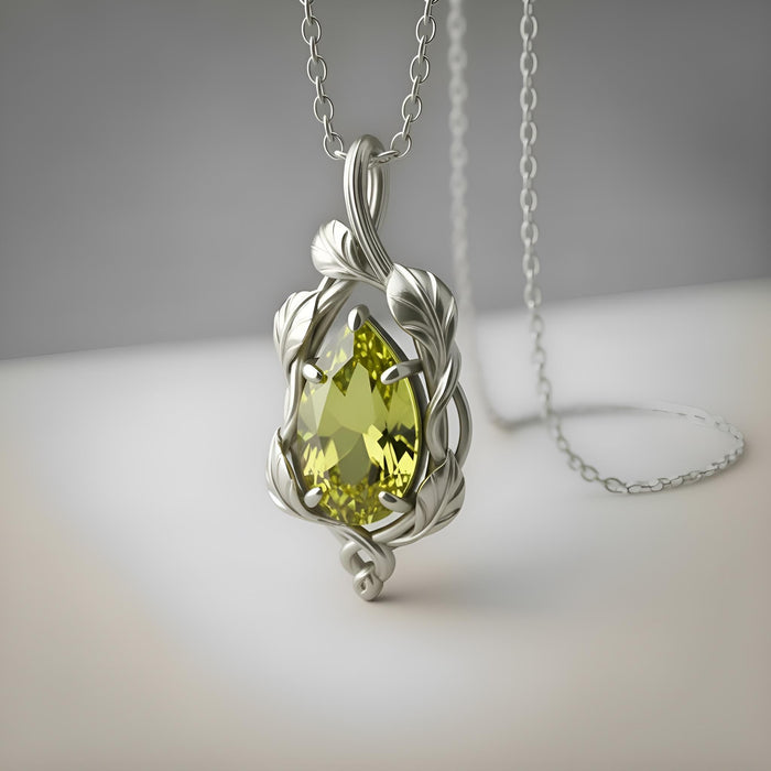 Silver leaf-and-vine pendant with a green pear-shaped stone on a neutral surface