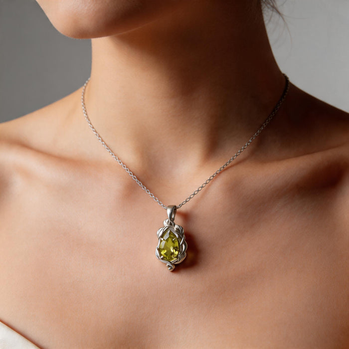 Person wearing a silver leaf-and-vine pendant with a green pear-shaped stone