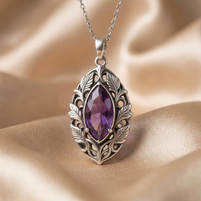 Front view of the elven necklace with a faceted violet marquise-shaped stone on draped beige fabric