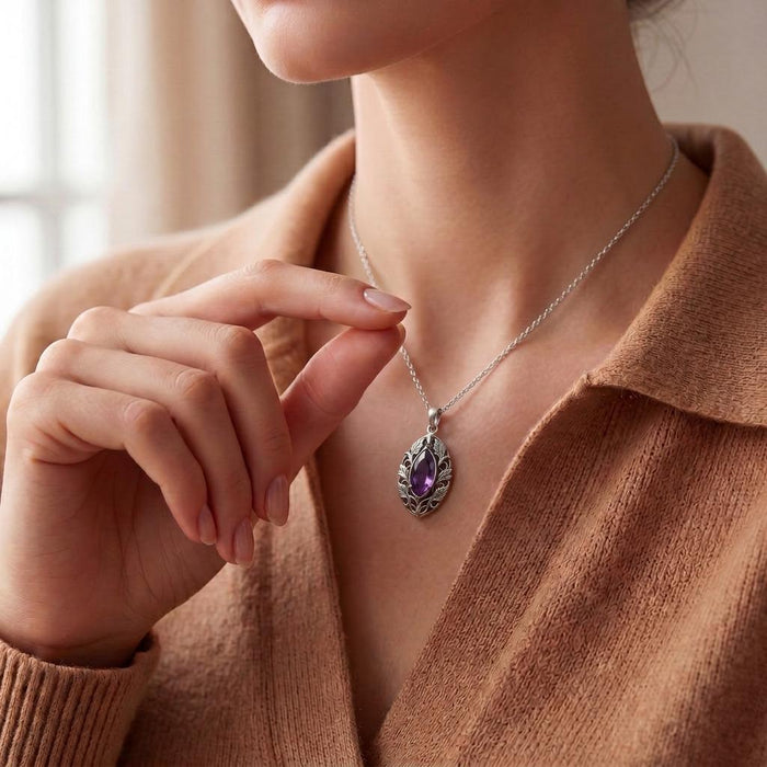 Model holding the chain of the Personalized Elven Amethyst Necklace with an openwork leaf frame