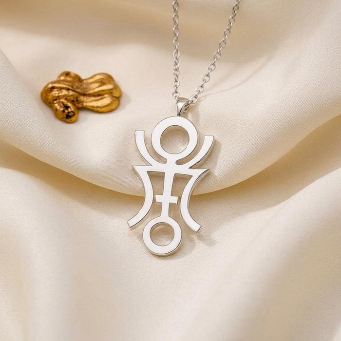 Phaëton openwork symbol pendant on ivory satin beside a gold-colored decorative object