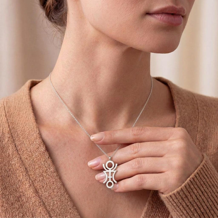 Close neckline view of a model holding the Phaëton Astrology Necklace pendant