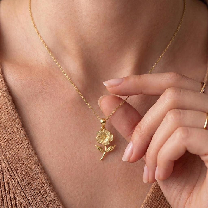 Gold Plated Silver phlox flower necklace worn at the neckline with a peach knit top
