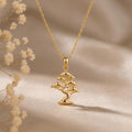 Gold Plated Silver Pine Crest Bonsai Pendant necklace with a winding trunk and three-tier canopy on neutral fabric