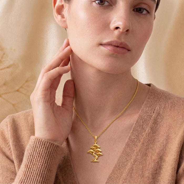 Gold Plated Silver Pine Crest Bonsai Pendant necklace worn at the collarbone with a neutral knit top