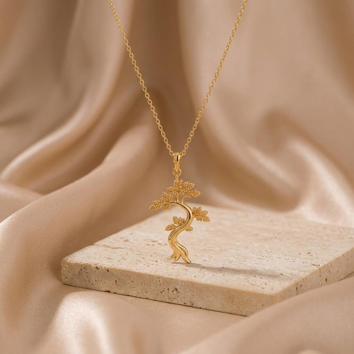 Gold Plated Silver Juniper Flame Pendant Necklace on a pale textured stone slab with satin background