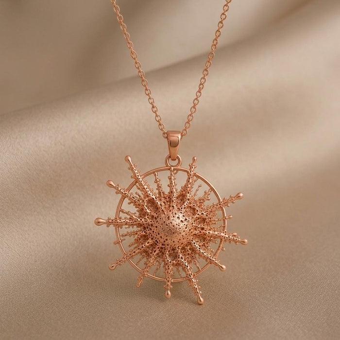 Rose Gold Plated Pollux Star Pendant Necklace with textured radiating rays on beige fabric