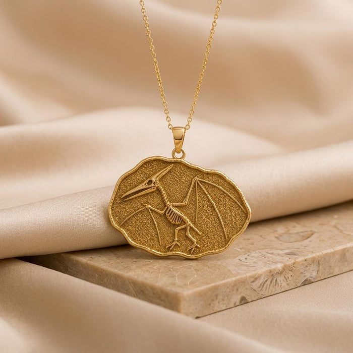 Gold Plated Silver Quetzalcoatlus fossil skeleton pendant on a stone display block