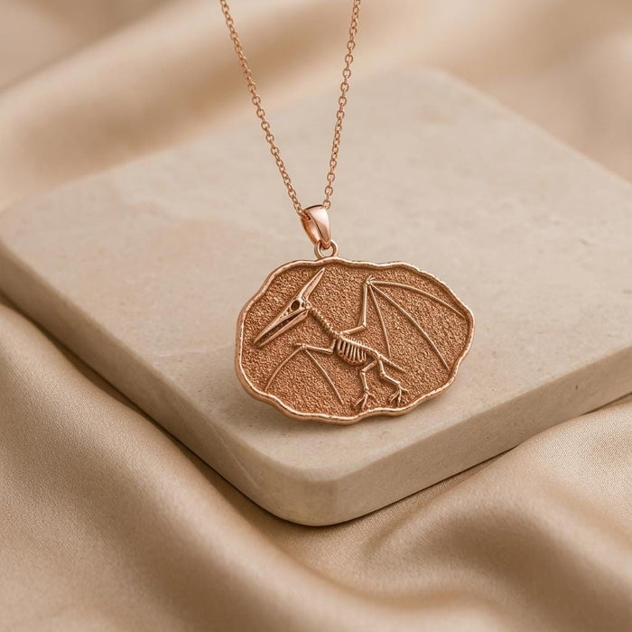 Rose Gold Plated Quetzalcoatlus Fossil Pendant Necklace on a pale stone block