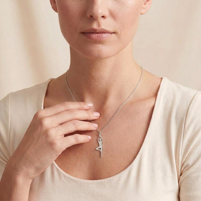 Raised-leg yoga figure necklace worn with a cream scoop-neck top