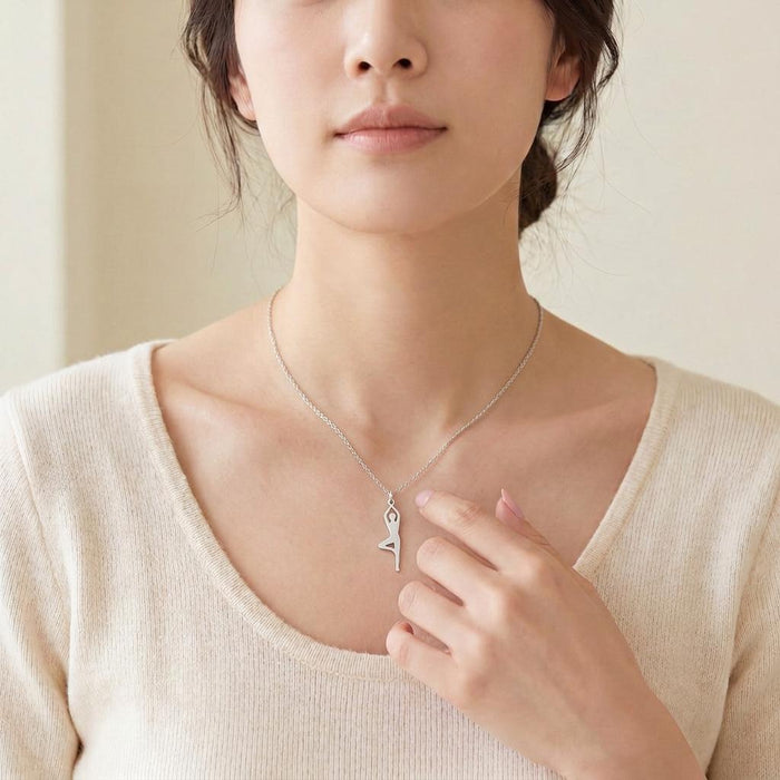 Raised-leg yoga figure necklace worn with a light knit top