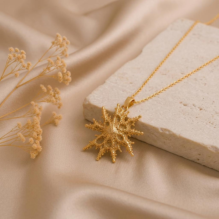 Gold Plated Silver Regulus Star Pendant Necklace beside dried flowers and a stone block