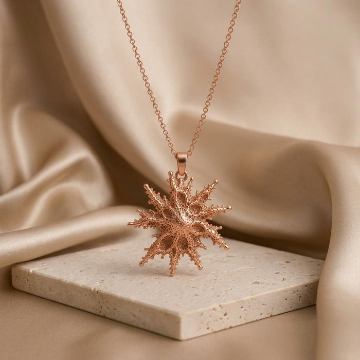 Rose Gold Plated Regulus Star Pendant Necklace displayed on a light stone block