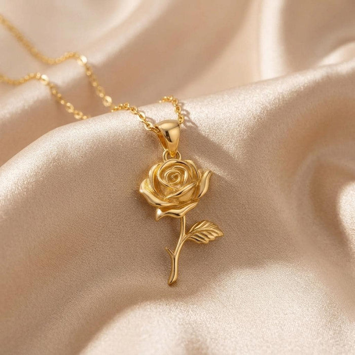 Gold Plated Silver Rose Flower Pendant Necklace with a layered spiral-petal rose bloom, curved stem, and textured leaf on champagne satin