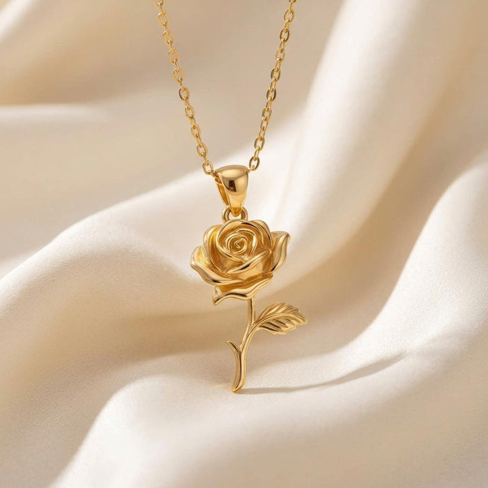 Close-up of a Gold Plated Silver Rose Flower Pendant Necklace with layered spiral petals and a textured leaf on ivory satin