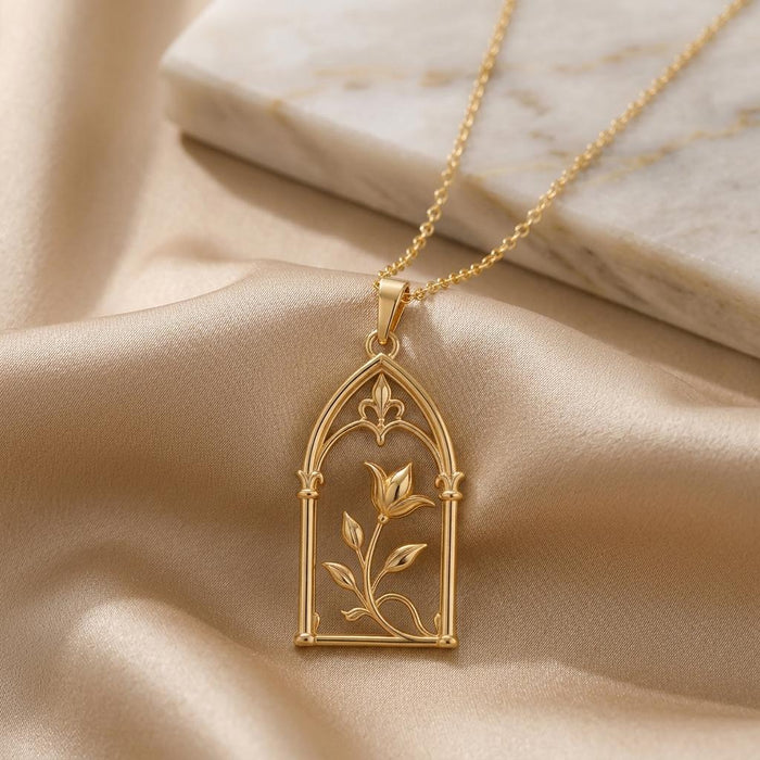 Gold-tone Royal Arch Bloom Necklace displayed on champagne satin beside a pale marble slab