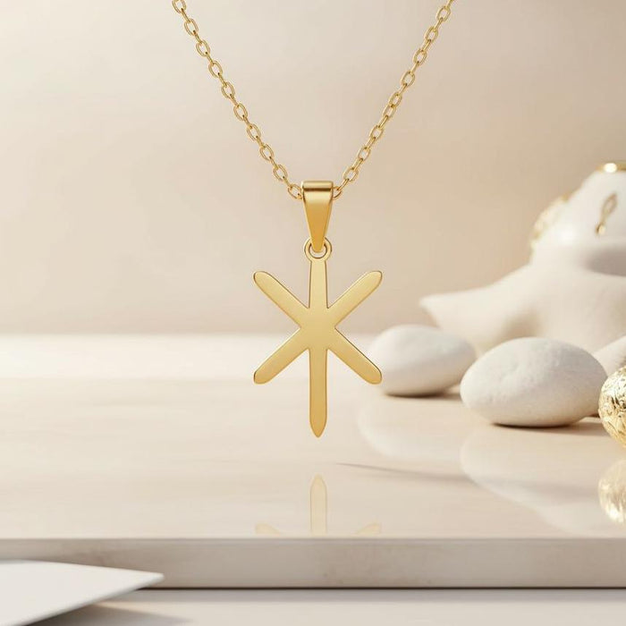 Gold Plated Silver Gebo Is bindrune pendant suspended above a cream tabletop