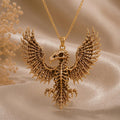 Gold-toned Sacred Eagle Skeleton pendant suspended above champagne satin with dried flowers at the left edge