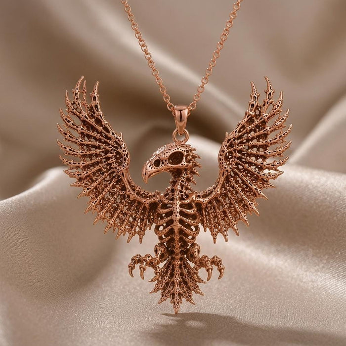 Rose-toned Sacred Eagle Skeleton pendant hanging above folded champagne satin