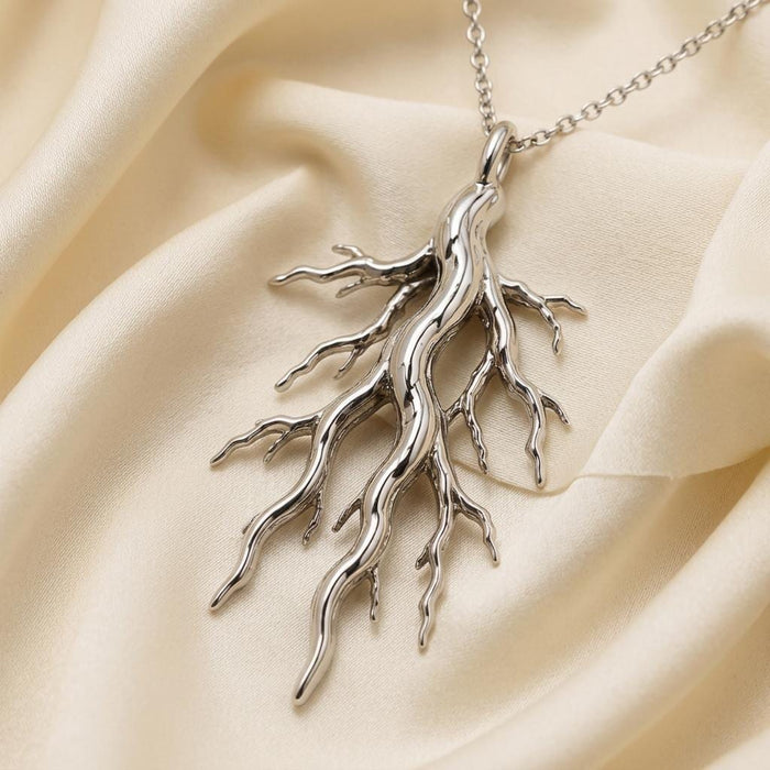 Silver Sacred Root Necklace with branching root pendant on folded cream satin