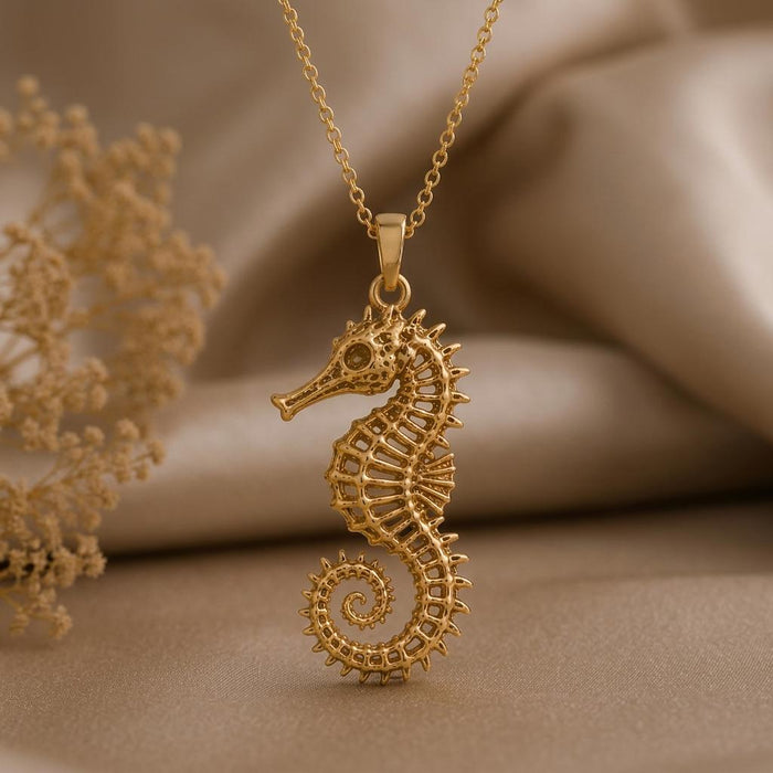 Gold Plated Silver Sacred Seahorse Pendant Necklace with openwork body and spiral tail on beige fabric