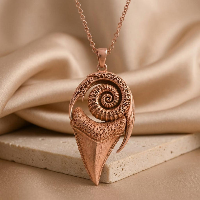 Rose Gold Plated spiral-and-tooth pendant standing against folds of ivory fabric on a stone tile