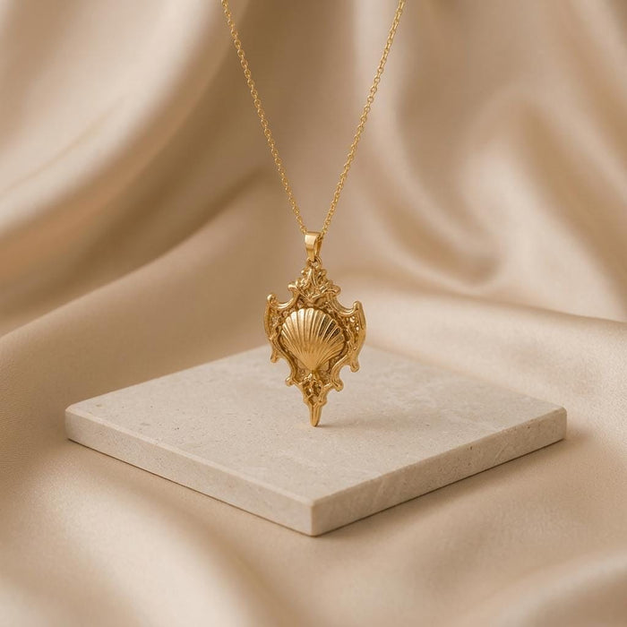 Gold Plated Silver Sacred Shell Relic shell pendant necklace displayed above a pale stone block