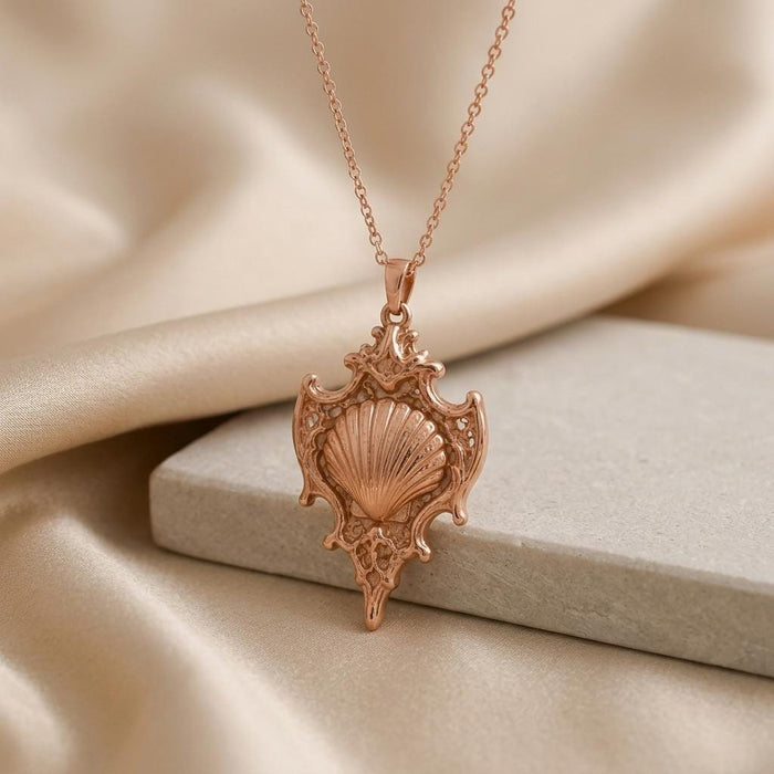 Rose-toned Sacred Shell Relic pendant necklace with ornate openwork shell frame on satin