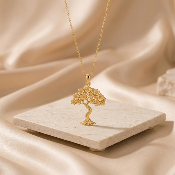 Gold Plated Silver Sakura Bloom tree pendant displayed above a pale stone platform